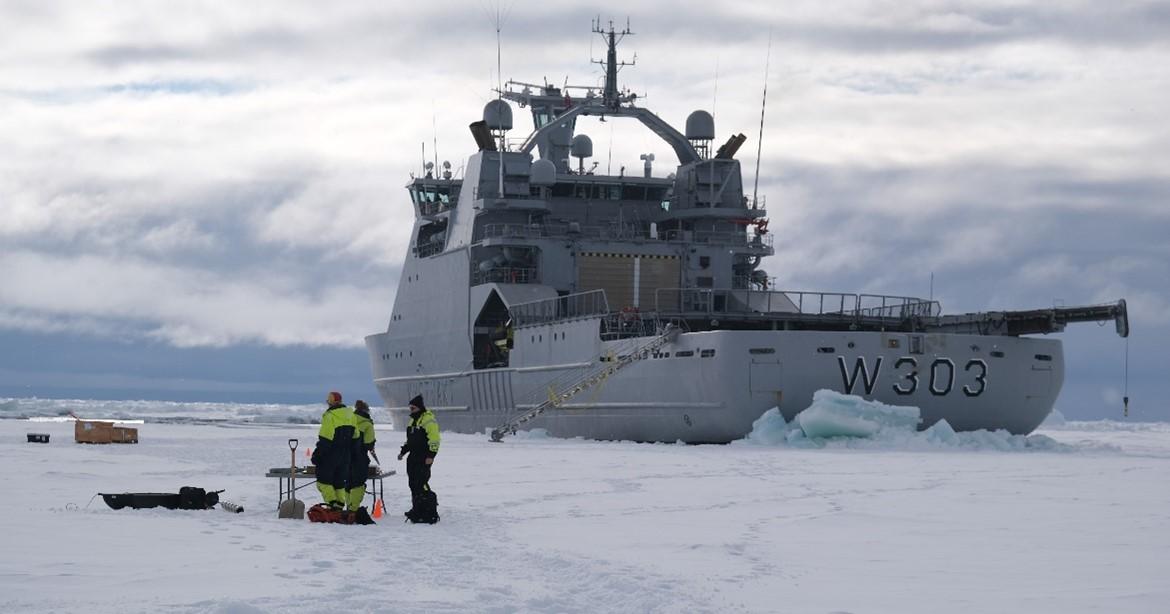 Forskere står på isen, bortenfor skipet KV Svalbard.  